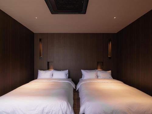 two beds in a room with white sheets at The Moor in Busan