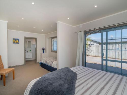 Un dormitorio con una cama y una puerta corrediza de vidrio. en Charming Family Retreat - Cozy 3 Bedroom & 3 Bathroom, en Whitianga