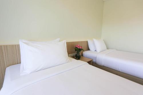 two beds in a hotel room with white pillows at Star 3 Hotel and Residence in Rayong