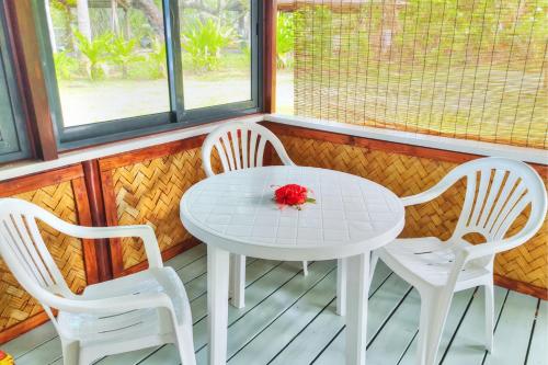 a white table and three chairs on a porch at TAHITI Tamanu House - Séjour Bord de mer, Plage privée, TV, Wifi, Hôte Polynésienne in Papehee