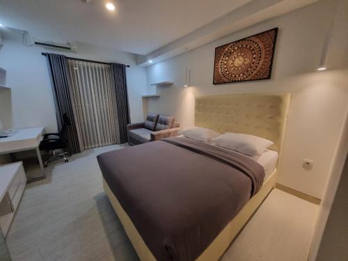 a bedroom with a bed and a desk and a chair at Studio Room Apartment with Pool in Yogyakarta