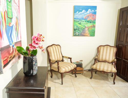 two chairs and a vase with flowers on a table at Hotel Los Altos Express "La Centroamerica" in Managua