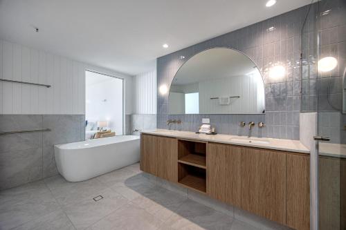 a bathroom with a tub and a sink and a mirror at Oceana On Broadbeach in Gold Coast