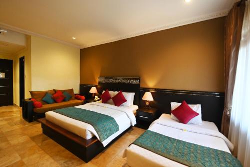 a hotel room with two beds and a couch at Puri Dewa Bharata Hotel & Villas in Legian