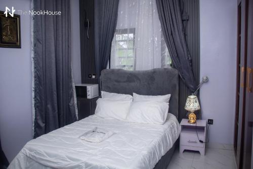 a bedroom with a bed with white sheets and a window at The NookHouse in Calabar