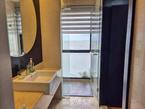 a bathroom with a sink and a glass shower door at Goldcoast Palm Tree Sepang Luxury Resort in Sungai Pelik