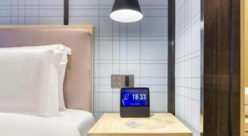 a clock sitting on a table next to a bed at Echarm Hotel Jingjiang Bus Passenger Station Fanggu Street in Jingjiang