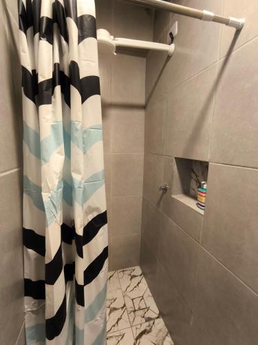 a bathroom with a shower with a black and white shower curtain at Mini Suite Comforto in Garanhuns