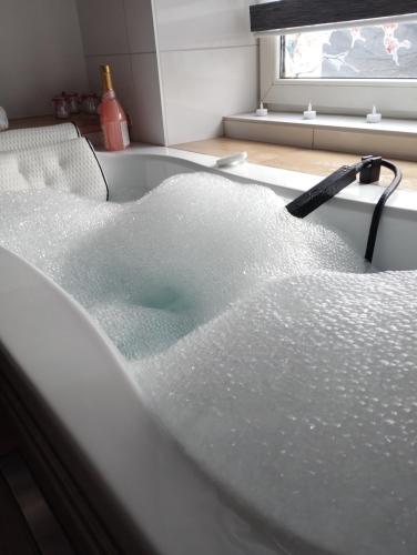 a bath tub filled with water with a hose at Apartment romantyczny SAKURA in Jędrzejów