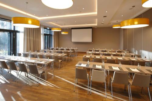 a conference room with tables and chairs and a screen at Romantik Hotel Kieler Kaufmann in Kiel