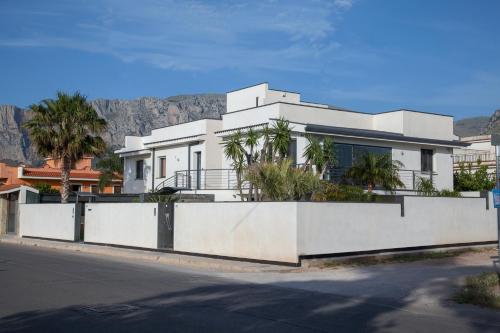 a white house with palm trees in front of a mountain at Tra Le Braccia di Morfeo in Terrasini