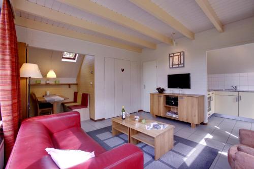 a living room with a red couch and a table at Buitenplaats Gerner in Dalfsen
