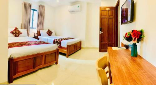 a hotel room with two beds and a table with flowers at Happy Beach Hotel in Nha Trang