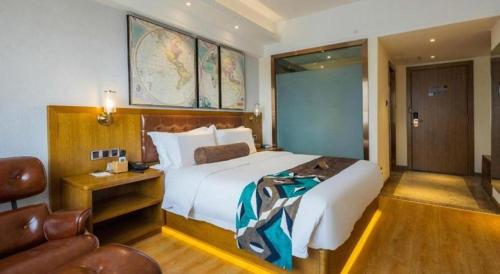 a hotel room with a large bed and a chair at James Joyce Coffetel Kunming Railway Station Huancheng Nan Road Metro Station in Kunming