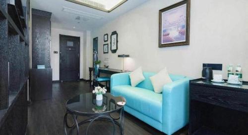 a living room with a blue couch and a table at Xana Hotelle Jinan Wuanfu Interchange Huafu International Square in Jinan