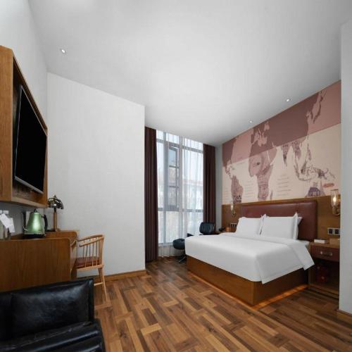 a bedroom with a large white bed and a couch at James Joyce Coffetel Luoyang Longmen High-speed Railway Station Baolong Plaza in Luoyang