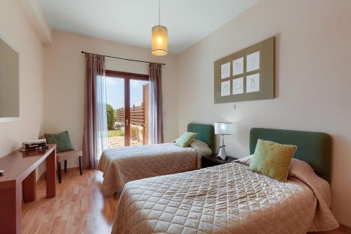 a hotel room with two beds and a desk and a window at Aphrodite Hills Junior Villas Junior Villa J032 Air Conditioning Private Pool 2 Bedrooms P in Paphos