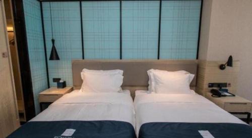 two beds in a room with two pillows at Echarm Hotel Hefei West Qilitang Metro Station in Hefei