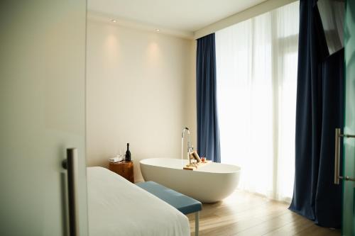 a bathroom with a tub and a bed and a sink at Hotel Mediterraneo in Sottomarina
