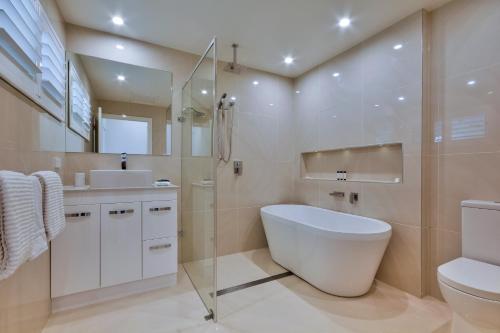 a bathroom with a tub and a toilet and a sink at Heliconia Grove - 1 bedroom - on Hamilton Island by HIHA in Hamilton Island