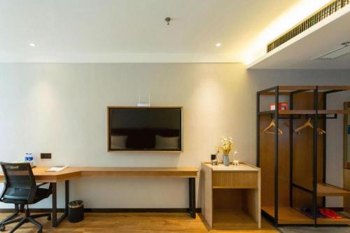a room with a desk and a television on a wall at GreenTree Inn Express Datong High-Speed Railway Station Wanda Plaza Fangte in Datong