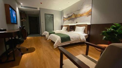 a bedroom with two beds and a desk and a television at GreenTree Inn Express Datong High-Speed Railway Station Wanda Plaza Fangte in Datong