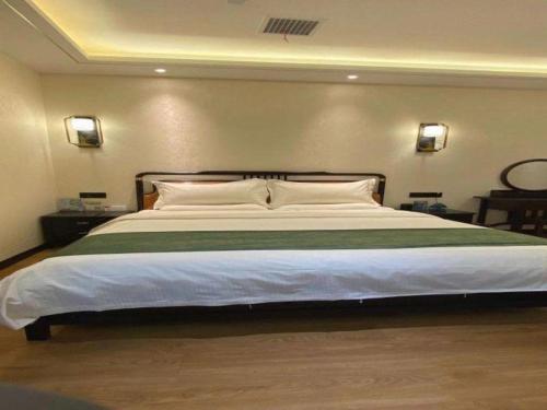 a large bed in a bedroom with two lights on the wall at GreenTree Inn Express Datong High-Speed Railway Station Wanda Plaza Fangte in Datong