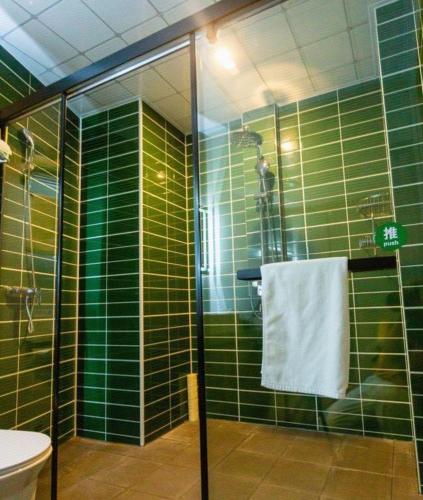 a green tiled bathroom with a shower and a toilet at GreenTree Inn Express Datong High-Speed Railway Station Wanda Plaza Fangte in Datong