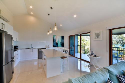 a kitchen and living room with white cabinets and a couch at Heliconia Grove - 1 bedroom - on Hamilton Island by HIHA in Hamilton Island