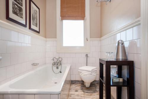 a bathroom with a tub and a toilet and a sink at Quarters Hotel in Durban