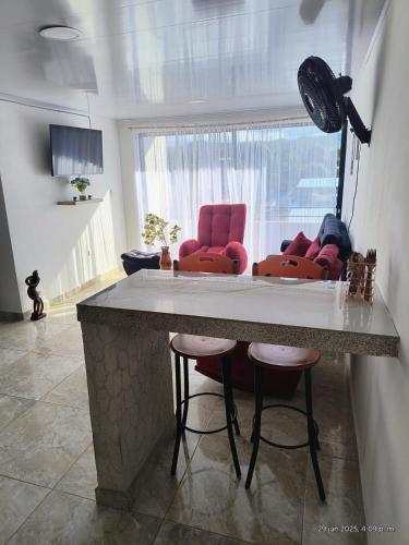 a kitchen with red bar stools and a living room at Apartamento Vacacional in Mariquita