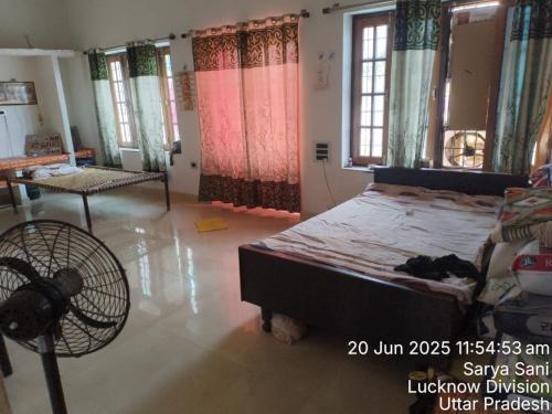 a bedroom with a bed and a fan and windows at Arvind maurya home stye in Naimishāranya