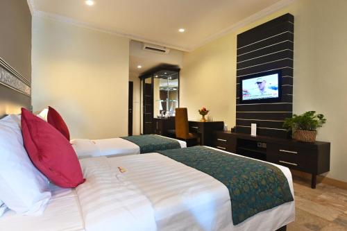 a hotel room with a bed and a flat screen tv at Puri Dewa Bharata Hotel & Villas in Legian