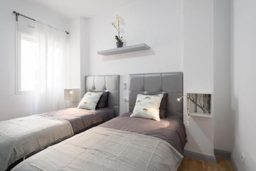 2 camas en una habitación con paredes blancas en MalagaSuite City Center Ollerías, en Málaga
