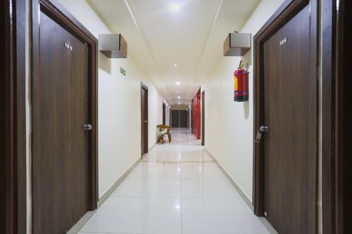 a corridor in a building with doors and white floors at Townhouse RIO in Hyderabad