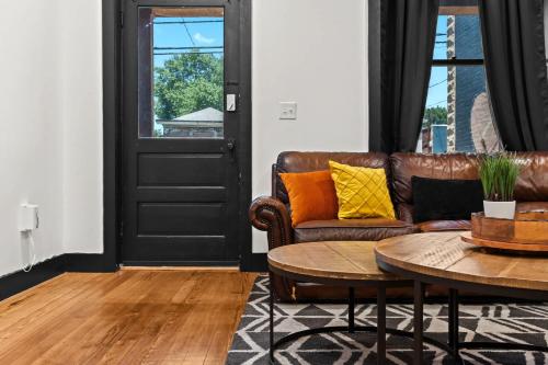 Una sala de estar con un sofá de cuero y una mesa. en Unique Black Home in the Heart of Shelby Park, en Louisville