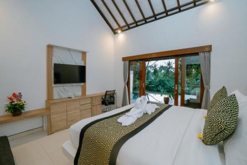 a bedroom with a large bed with a television and a bedzinski at Uma Jala Villa Ubud in Ubud