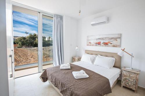 ein Schlafzimmer mit einem Bett und einem großen Fenster in der Unterkunft Villa Olive Thalassa, Brand New, Luxury 3Bdr Protaras Villa With Private Pool in Protaras
