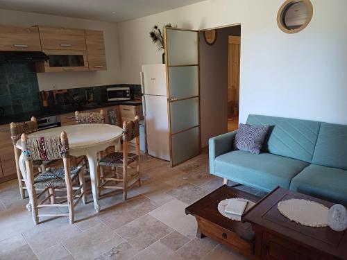 un salon avec une table et un canapé bleu dans l'établissement Charmant T1 en Provence Verte, à Carcès
