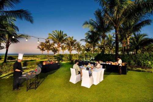 a restaurant with people sitting at tables on the grass at Hoi An Royal Beachfront Villas in Dien Ban