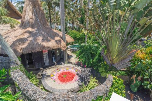 a garden with a small house with a red flower at Authentic beachfront Villa Owl in Krambitan