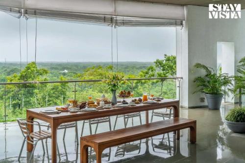 アリバグにあるStayVista at Villa Ekanta with BBQの大きな窓のある部屋で、テーブルと食べ物を用意しています。
