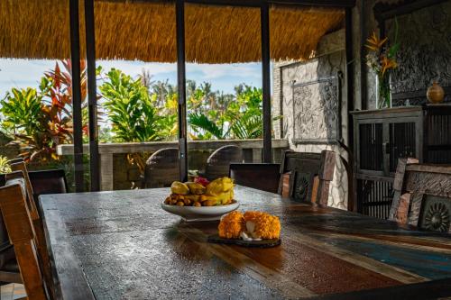 a table with a bowl of fruit on top of it at Authentic beachfront Villa Owl in Krambitan