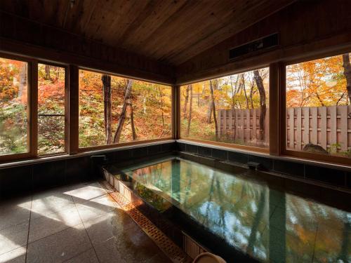 een zwembad in een kamer met ramen bij Nakaodaira in Takayama