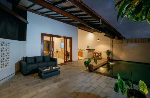 a living room with a couch and a swimming pool at Uma Jala Villa Ubud in Ubud