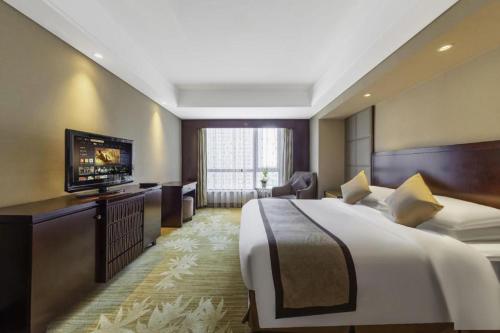 a hotel room with a bed and a flat screen tv at Hohhot Hai Liang Plaza Hotel in Hohhot