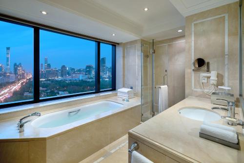 a bathroom with a bath tub and a large window at The Kunlun Beijing Jin Jiang Radisson in Beijing