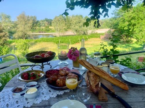 una mesa con comida, pan y bebidas. en La Chaumière DE L'EAU SAUVAGE, en Villeneuve-sur-Allier