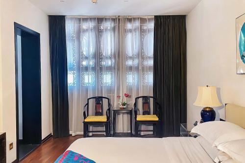 a bedroom with a bed and two chairs in front of a window at No.3 Garden Hotel in Pi-chi Kuan