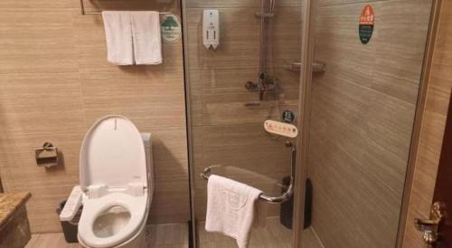 a bathroom with a toilet and a shower with towels at GreenTree Inn Taiyuan PinGYAng Road Business Hotel in Taiyuan